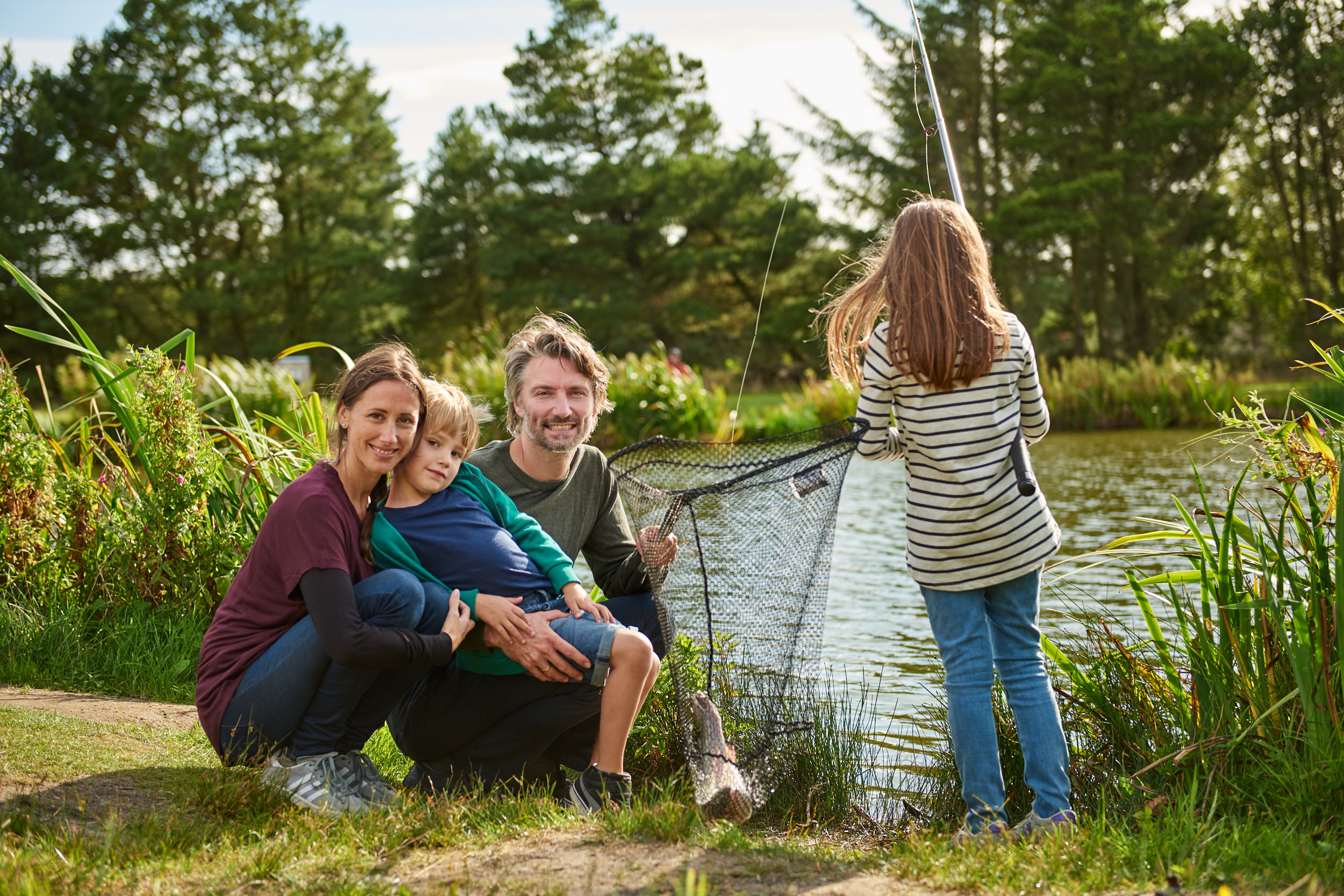 Familie ved sø fanger fisk - turist fotograf - attraktion